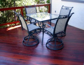 A custom hardwood deck built with Tiger Wood. It includes a wood railing with metal balusters.
