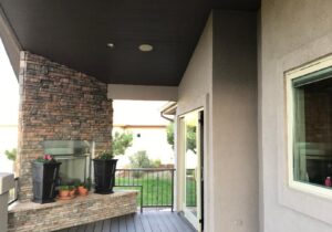 A composite, covered deck with a custom, stone, gas fireplace in one corner of the deck.