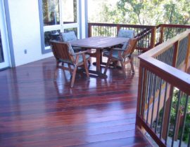 An elevated deck built using Tiger Wood laid at 45-degrees. It has a wood railing with round metal balusters and drink cap.