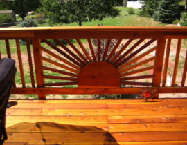 Custom designed sunburst design panel in a redwood picket fence railing.