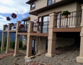 The wrought iron railing that the homeowner designed is anchored by stucco columns with concrete stone toppers.