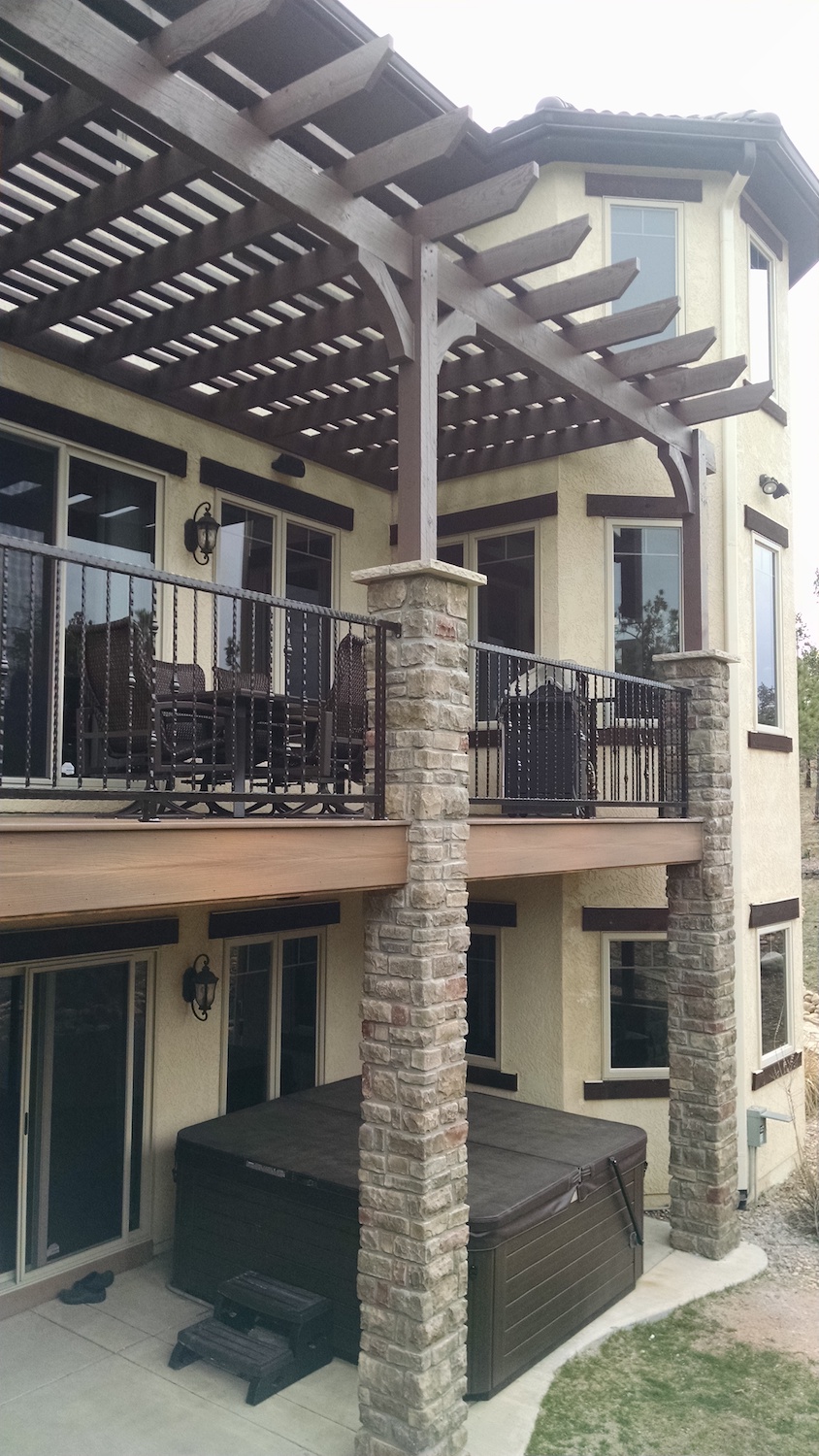 Custom built wrought iron railing between stone columns on composite deck