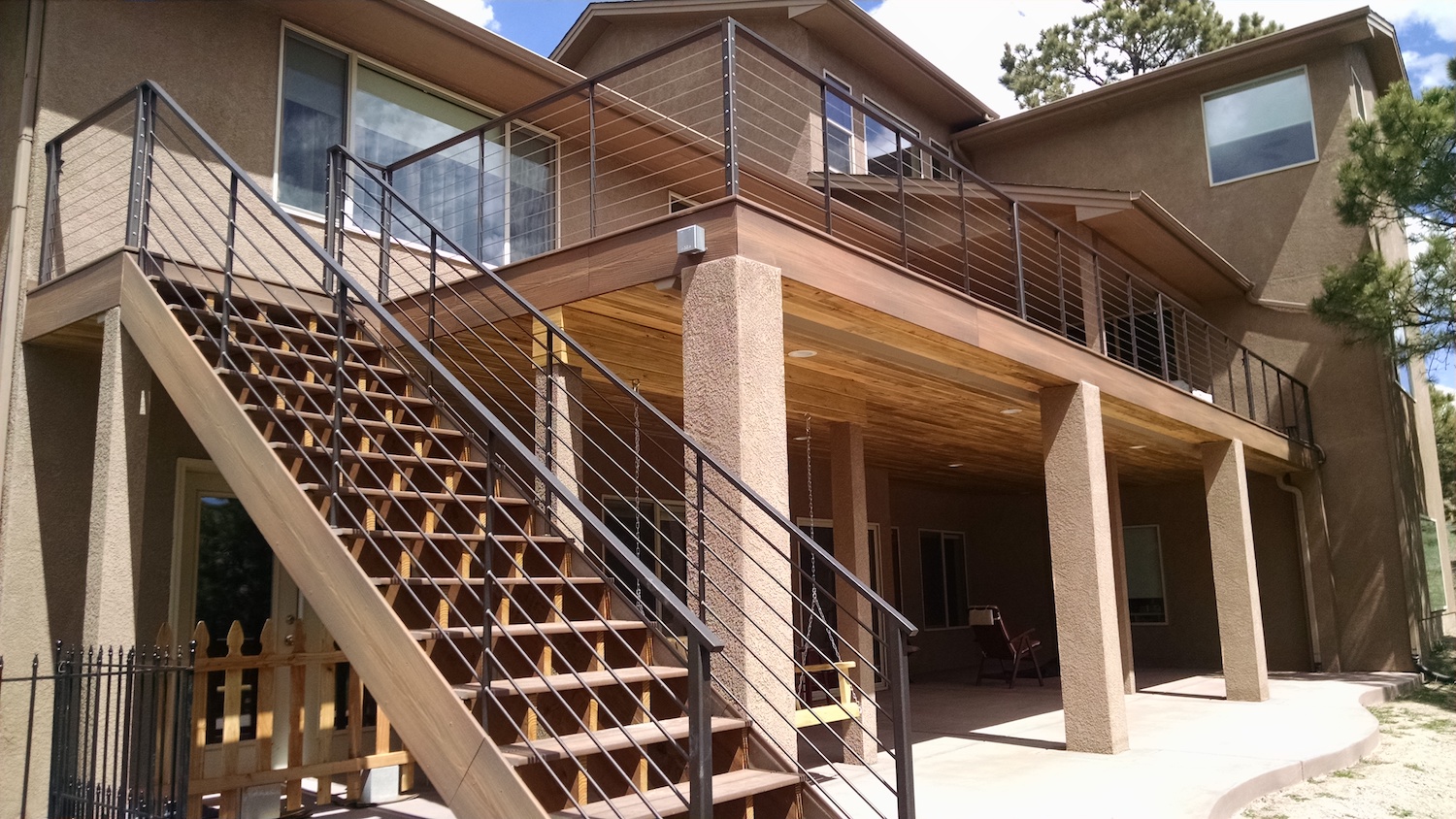Elevated composite deck with custom deck railing. Trex RainEscape system added
