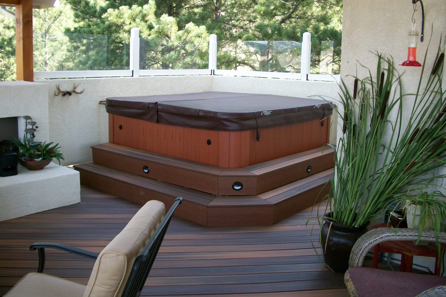 Composite deck with a hot tub, stucco half-walls, and steps built to the hot tub.