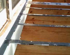 This shows a wood deck frame with flashing and protector tape to prevent against water damage.