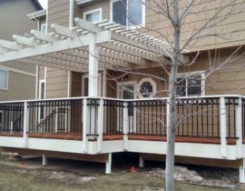 The full view of the deck shows the Cedar pergola. The railing has wood components with metal panels and custom ring top accent panel.
