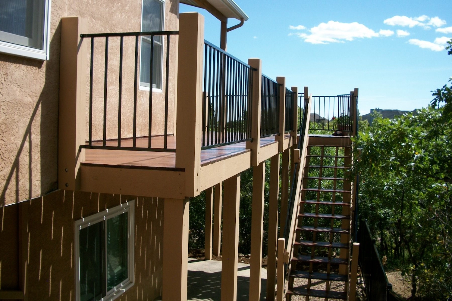 Custom hardwood deck that wraps around the side of the house with a staircase to ground level