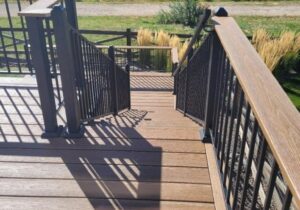 This composite deck features a Fortress Fe26 railing. It has 3x3 posts with caps and a composite drink cap. We also installed a hand rail on one side of the stairs.