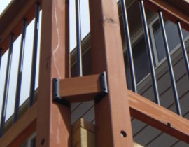 A corner of the deck showing round metal balusters with wood posts and rails.