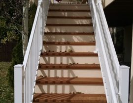 This staircase is 3'-wide with closed steps. The tread is stained in a wood color and the risers in a white for a beautiful contrast. The railing is a white, aluminum panel rail system with a handrail.