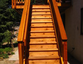 Custom redwood deck with 3'-wide, closed steps, wood railing, drink cap, and handrail.