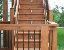 3'-wide, closed step staircase with a 90-degree turn landing, step lights, and a wood/metal railing with handrail.