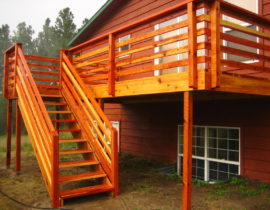 A redwood deck with 3-wide, open staircase a custom wood railing featuring horizontal railings instead of vertical balusters.