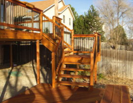 This elevated redwood deck has a 3'-wide, open staircase with 180-degree turn landing leading to a ground level deck area.