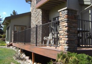 Composite decking and fascia. Metal panel railing anchored by custom stone columns.