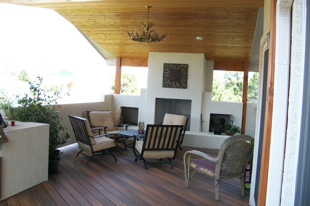 Composite deck with tongue and groove deck cover and stucco wood-burning fireplace.