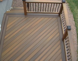 A composite deck with boards laid at 45-degrees and a double picture frame in a contrasting color. The railing has composite components and metal Vienna-style balusters and composite drink cap.