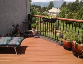 Redwood deck with 45-degree angle design and a double picture frame stained in a contrasting color. The railing is a metal panel rail system with wood drink cap.