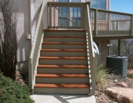 This shows a deck with the decking and step treads in one solid body stain color while the railing, drink cap, and stair risers are in a contrasting stain color.