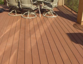 Composite decking laid out at 90-degrees with no divider boards. The railing is a metal panel system attached to stucco columns.