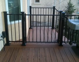 Composite decking laid at 90-degrees with double divider and end boards. The metal panel railing system also includes a gate at the top of the stairs.