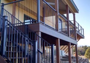 This composite deck was built with a metal railing system that has vertical, stainless steel cables instead of balusters. On the stairs, the customers went with standard metal balusters instead of the cables.