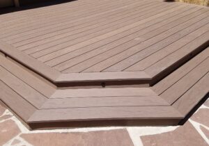 This ground level deck was built with composite decking material and a single picture frame with a wrap around stair in the same material.