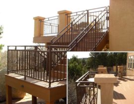 A composite deck with stucco columns and a staircase that has a 180-degree turn. The railing is a metal panel system with divided top accent panel and a matching gate at the top of the stairs.
