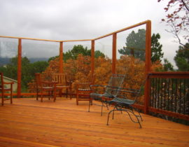 DBS built this custom deck using redwood laid at 45-degrees. The railing features redwood components with drink cap and round, metal balusters in black. We also installed installed a custom glass wall system to provide a windbreak that would not disrupt the homeowners' view.