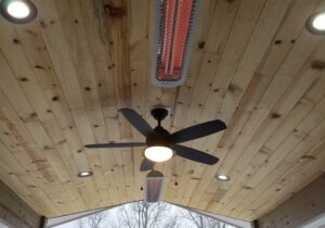 This gabled deck cover has a vaulted ceiling built with Blue Stain tongue and groove pine. We have installed recessed lights, a ceiling fan, and two overhead heaters.