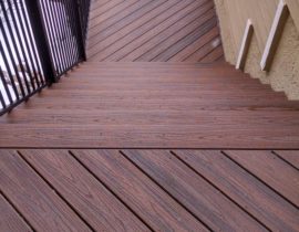 Deck boards are laid at alternating 45-degree angles on this deck. The railing is black metal panel system with handrail.