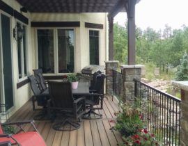This gorgeous, custom deck features boards at 90-degrees with a single divider board and a Cedar pergola. The railing is a custom design in wrought iron and anchored by stone columns.