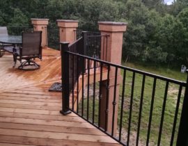 This custom built, heart redwood deck has the decking laid out in a herringbone design with divider boards. We added large stucco columns that have stone toppers. The metal panel railing features a knuckle design on the balusters.