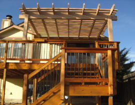 This is a redwood deck built with a railing that has wood components and drink cap and round metal balusters. There is a 90-degree turn landing on the stairs. We also built a cedar pergola over part of the deck to provide some shade.