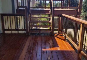Our customer had us build two decks at different heights, but attached by a set of stairs. The redwood decking is laid at 90-degrees and the railing has wood components and drink cap with round metal balusters.
