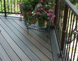 A composite deck with the boards at 45-degrees and a double picture frame. The railing is a metal panel system with twisted balusters and basket designs.