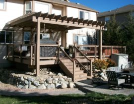 A composite deck with a pergola stained to match the house trim.