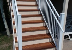The new stairs are 4'-wide closed steps with the risers stained in white. The white aluminum stair railing also has a handrail on one side.