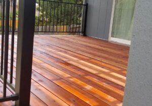 This is a gorgeous redwood deck with the boards laid a 90-degree angle to the joists. The railing is a black, metal panel railing system with 3