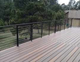 A composite deck with a gorgeous, matte black, metal railing featuring horizontal stainless steel cables.