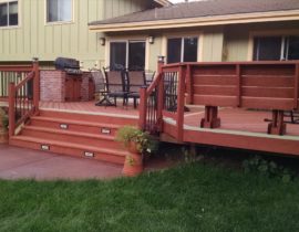 Redwood deck with a herringbone design. The picture frame and dividing board are stained in a contrasting color. We also added a built-in, brick cooking area for the homeowner.