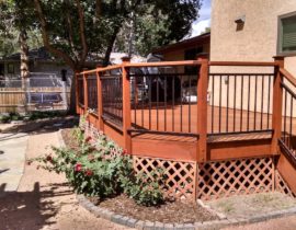 This redwood deck features a railing with wood posts and drink cap with a metal panel rail set below the drink cap. We also installed post caps on all the posts.