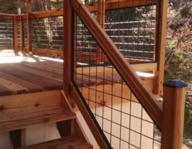 This redwood deck features a Wild Hog railing system with wood components. The panels are metal grid in matte black.