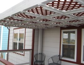 This pergola was built with the top laid out in a grid pattern stained in white. Then a red lattice was laid over the top of that to provide a look that matches the house.