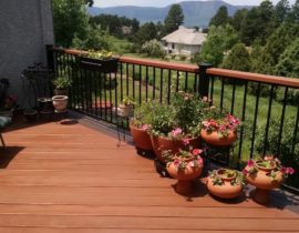 Redwood decking laid at a 45-degree angle, with a double picture frame stained in a contrasting color. The railing is a metal panel railing system with a redwood drink cap.