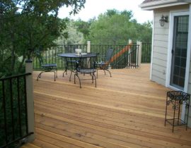 A redwood deck with the boards laid at 45-degrees. The railing has wood posts that have been stained with a solid body stain and metal panels in matte black.