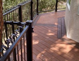 A heart redwood deck with a double picture frame that is stained in a contrasting color. The railing is a custom, wrought iron design.