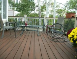 Decking is laid out at a 90-degree angle to the joists. The railing has composite components and drink with round metal balusters.