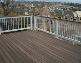 The deck boards are laid out at 90-degrees. The railing is wood components, round metal balusters, and a composite drink cap.