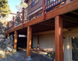 This redwood deck features a wood and metal railing system. The posts are redwood and each one has a post cap light on top. The metal panels between posts are in a matte black color.